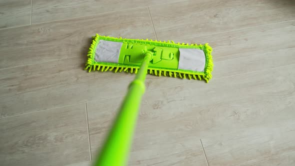 New green mop moving on parquet floor alt