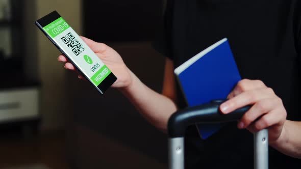 Woman Demonstrates Smartphone with Vaccination Passport Allowing Travel in Suitcase alt