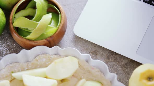 Laptop with apple tart and peeled green apple alt