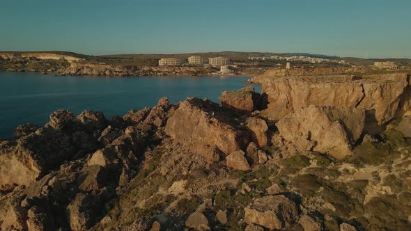 Beautiful mediterranean dry and rocky landscape on the seashore with a peaceful village in the backg alt