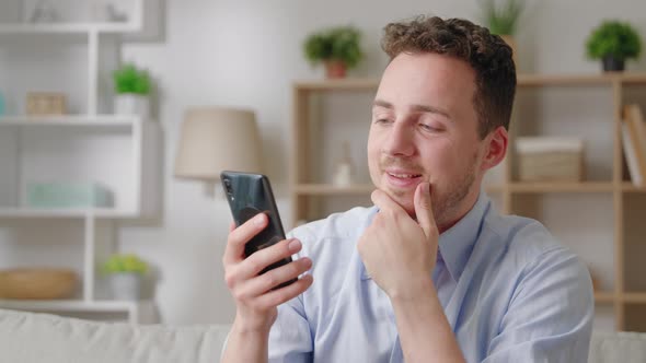 Satisfied Smiling 30s Millennial Sit on Sofa Using Cellphone Device Share Sms Social Media Network alt