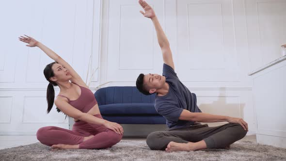 Asian couple practicing yoga at home together