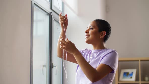 African Woman Closes Window Blinds at Home alt