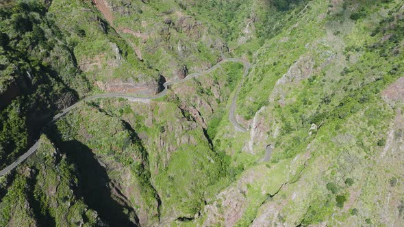 Scenic mountainous road curving along dramatic valley, Madeira; aerial alt