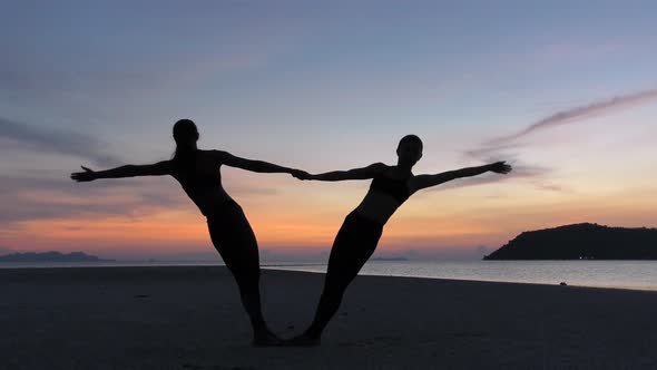 Women Practicing Yoga Together at Sunset Sea