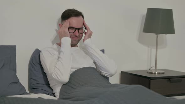 Casual Man Having Headache While Sitting in Bed alt