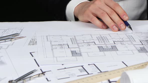 Engineer Sits at the Table Examines the Drawing of the New Store. Close Up alt