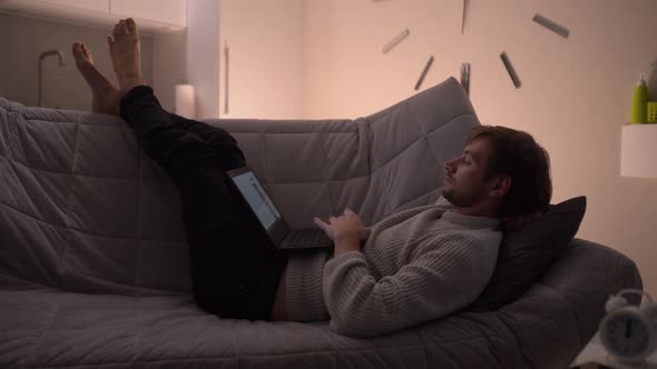 A Man Lying in Bed Uses a Laptop
