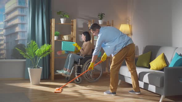 a Couple of Spouses a Young Disabled Woman in a Wheelchair are Cleaning the House alt