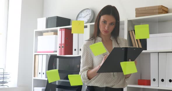 Businesswoman Making Notes in Documents Standing Near Glass Wall