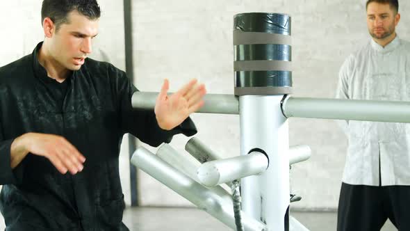 Kung fu fighter practicing martial arts with wooden dummy 4k alt