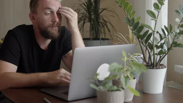 Man with a Beard Uses a Laptop