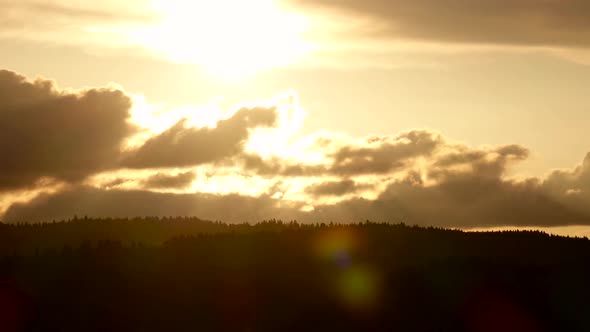 Sunset in Clouds and Over Tops Fir Trees. Time Lapse alt