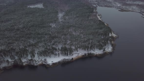 Aerial footage of russian winter forest with trees, spruces and snow near the lake