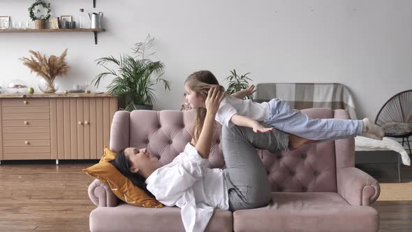 Young Mom Kid Girl Playing at Home Child Flying in Mothers Arms Having Fun alt