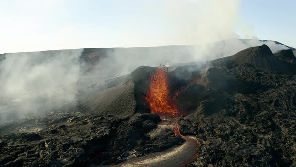 Aerial flight towards spectacular volcanic eruption with spewing lava from crater. Close up flyover. alt