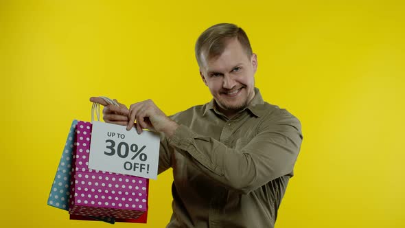 Man Showing Up To 30 Percent Off Inscription and Shopping Bags, Looking Satisfied with Low Prices alt