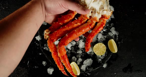 A Man's Hand Puts a Boiled Crab on a Stone Board with Ice. 