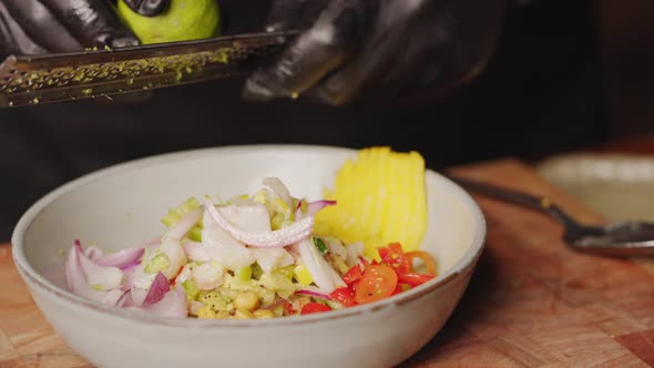 Preparation of Ceviche - slow motion close up shot of a chef holding grater, grating lime into a bow alt