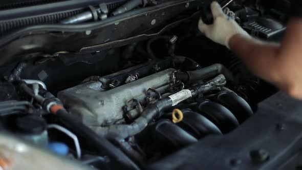 Male Auto Mechanic Changes Spark Plugs in a Car Engine