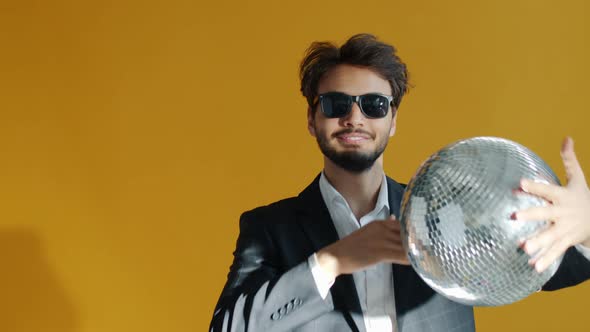 Slow Motion Portrait of Goodlooking Arab Guy Enjoying Party Dancing with Mirrorball alt