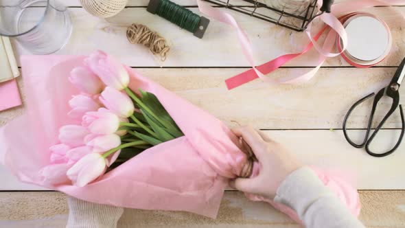 Step by step. Florist wrapping pink tulips in bouquet. alt