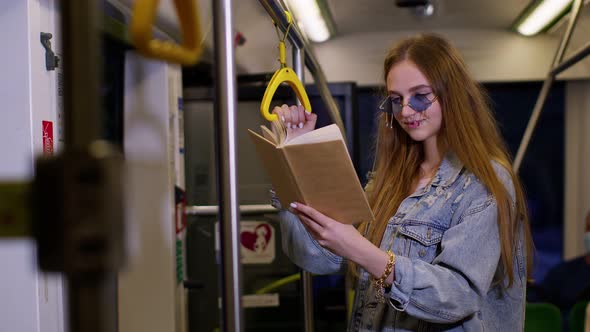 Portrait of Attractive Young Adult Woman Stay at Empty Subway Train and Reading Interesting Book alt