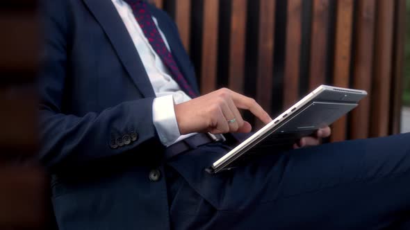 Close Up Businessman in Official Dark Blue Suit Sits on Bench in Park Before Meeting with Partners alt