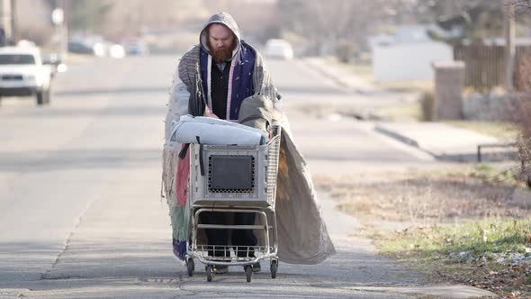 Homeless man pushing shopping cart down the street alt