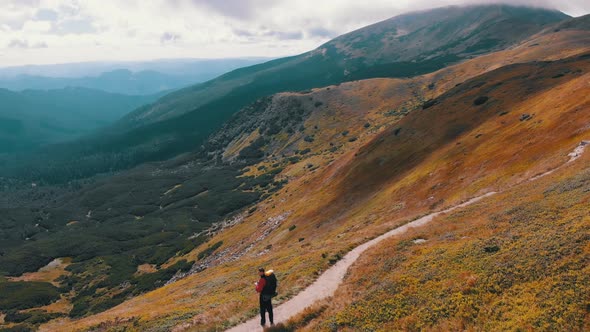 Aerial View of a Traveler with Backpack Climbing Along Mountain Slope. Epic Shot alt