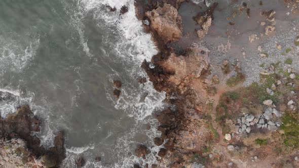 Aerial view of foaming sea waves crashing against rocky shore, coastline Crete Greece. Nature