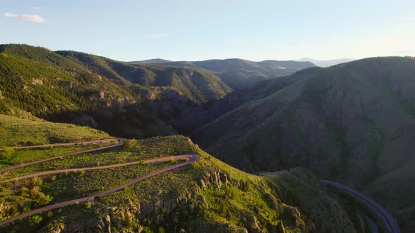 Drone Footage Of Winding Road On Mountain During Beautiful Golden Hour Sunset. Drone Flying Backward alt