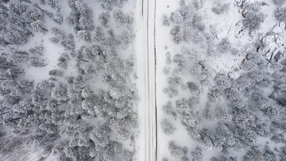 Aerial overhead drone view of snowy unplowed back roads in Colorado surrounded by snow and ice cover alt