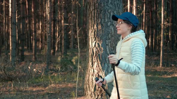 Active Tourist Woman in Cap and Glasses During Nordic Walking alt
