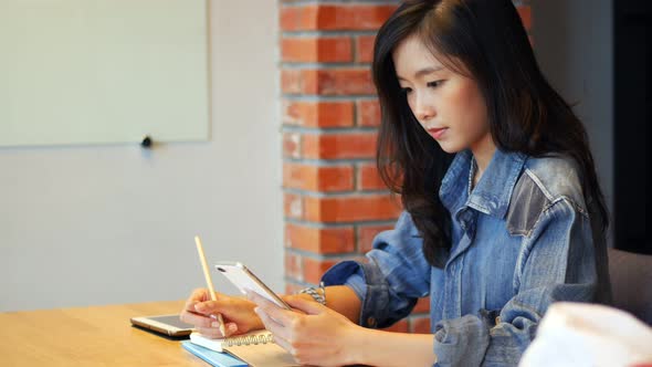 Businesswoman owners using app smartphones and take notes in the office.