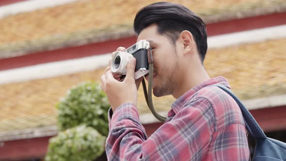 Attractive young Asian man tourists traveling and taking a photo in temple Thailand.