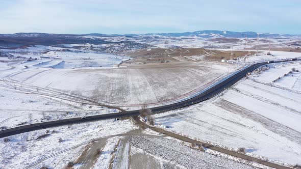 Flying Above a Winding Road With Driving Cars in a Frosty Winter Sunny Day alt