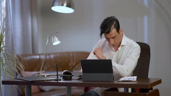 Concentrated Middle Eastern Man Sitting in Home Office Working Online in the Evening alt