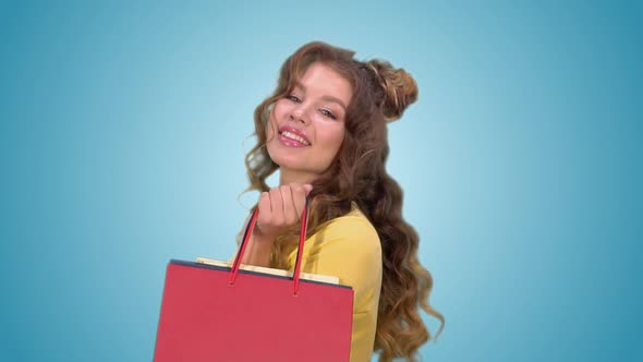 Beautiful Young Girl with Shopping Bags Spinning Around Herself and Posing Looking at the Camera alt