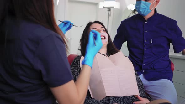 Doctors Dentists Woman and Man in Medical Masks Serve Patient in Dental Clinic alt