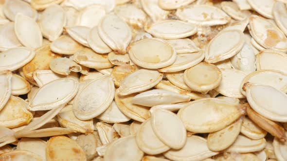 Organic pumpkin seed pile aftrer roasting and salting close-up 4K 2160p 30fps UltraHD panning footag alt