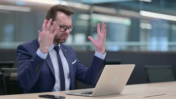Middle Aged Businessman with Laptop Reacting to Loss alt