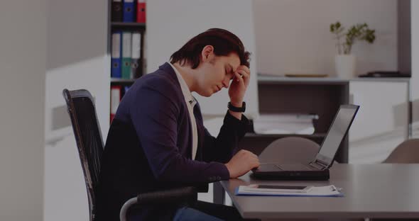 Tensed Businessman Using Laptop in Office alt