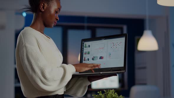 African Freelancer Typing on Laptop Late at Night Standing in Start Up Office alt