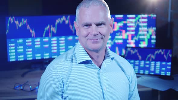 Male Broker Next to the Monitors Showing Stock Market Data alt