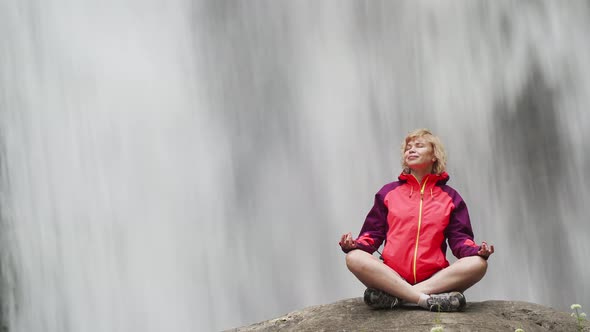 Woman Doing Yoga Pose Lotus at Big Waterfall