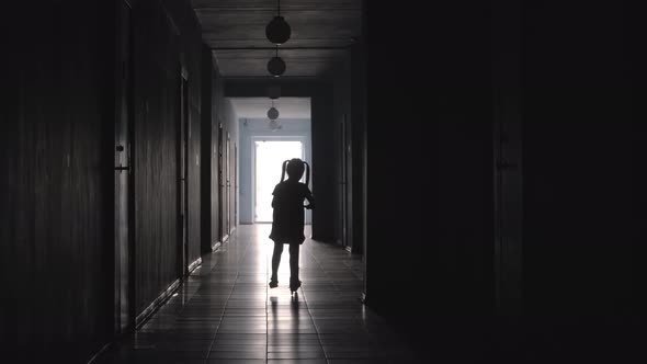 Silhouette of Little Girl Riding Scooter along Hallway