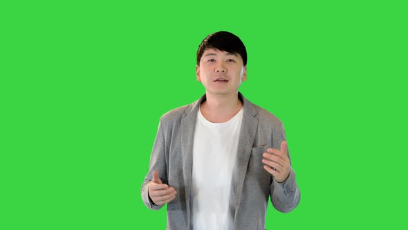 Young Asian Man Walks Telling Something on a Green Screen Chroma Key alt