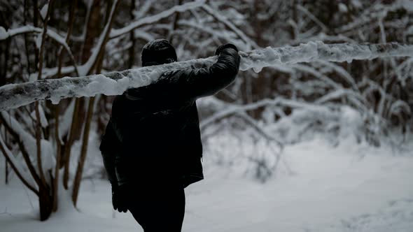 Man is Carrying Log in Forest in Winter Day Training Outdoors or Working in Woodland alt