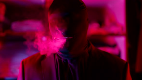 a Man in a Black Knitted Mask Without Eyes Lets Out a Stream of Smoke From Mouth in a Neon Flashing alt